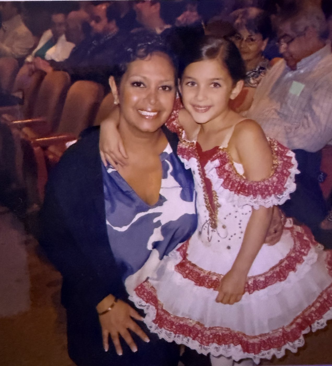 Farah smiling with her daughter Ava, who is wearing a red and white dance costume at a recital